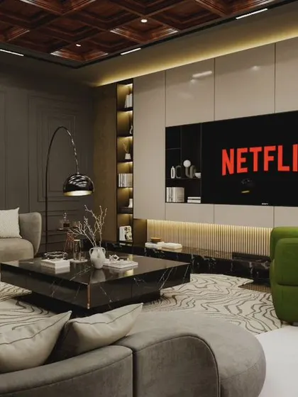 A modern entertainment room designed for relaxing and watching movies. The space features a large screen, comfortable curved sofas, and pops of green from the armchairs, all set against a sophisticated grey and wood palette.