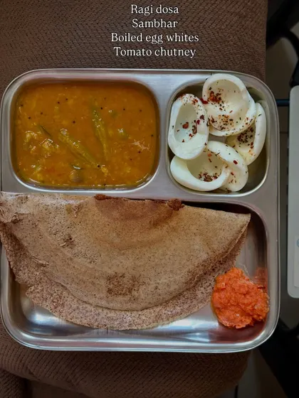 A healthy South Indian breakfast of ragi dosa served with sambar, boiled egg whites, and tomato chutney.
