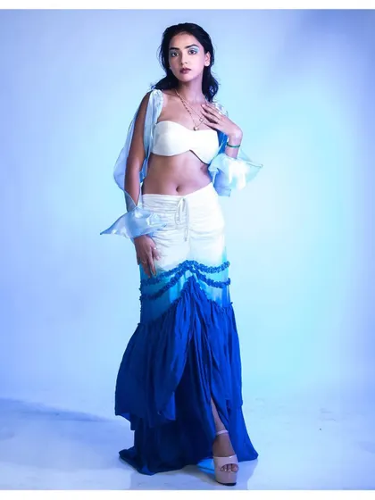 The complete look, showing the full length of the tiered, ocean-inspired skirt. The soft, diffused blue light gives the entire scene a dreamy quality.