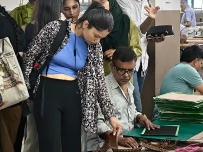 A student closely observes the fine craftsmanship of leather goods at Savi Fashion Apparel Pvt. Ltd. in Noida.