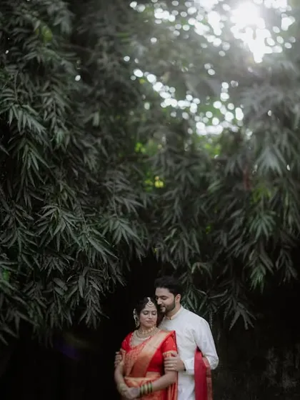 The same portrait as 169, but in color. This version highlights the rich red of the bride's saree against the lush green background, creating a warm and romantic mood.