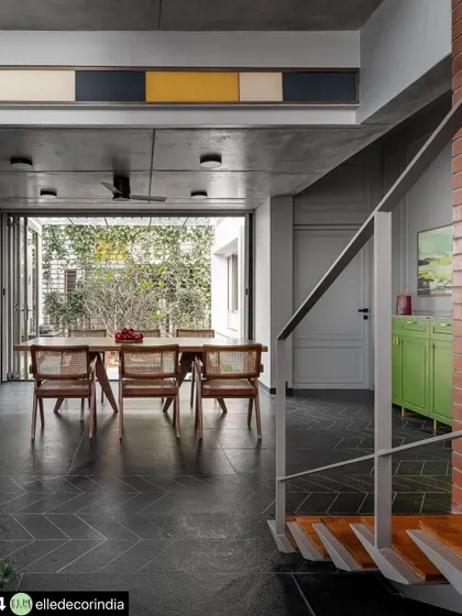 From this angle, you can see the interplay of materials and sightlines. The metal staircase railing frames the view into the dining room, which opens directly to the garden, highlighting the home's continuous flow between spaces.
