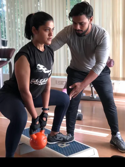 Proper form is everything. Here, I am guiding a client through a kettlebell squat, ensuring her technique is perfect to maximize results and prevent injury. This is the level of personal attention you get in every 1-on-1 session.