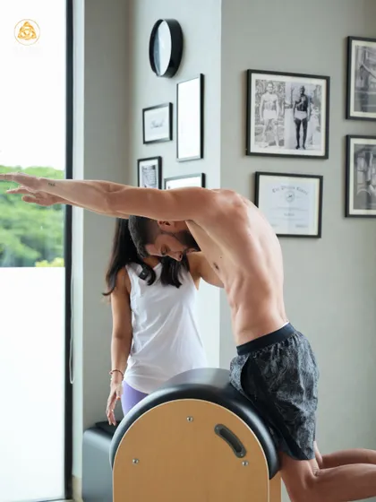 Pilates is for men too. Here, I'm guiding a client through a spinal extension on the Ladder Barrel, an exercise that is fantastic for improving posture and back strength.