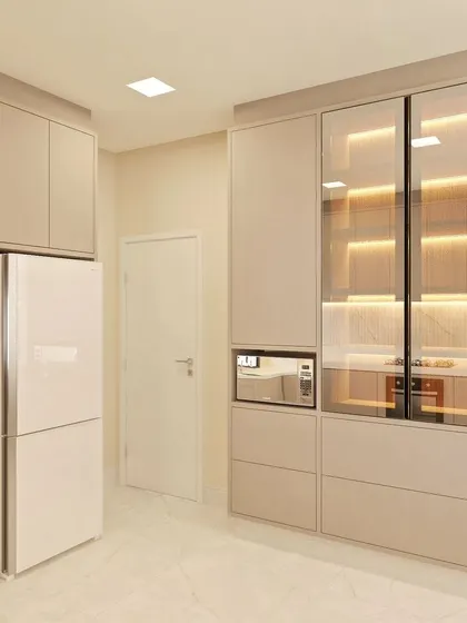 A tall unit in a beige kitchen, designed to house a built-in oven and microwave, along with a glass-front crockery display.