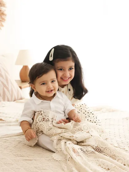 A sweet and gentle moment between an older sister and her baby brother. Her protective embrace and their shared smile make for a heartwarming sibling portrait.