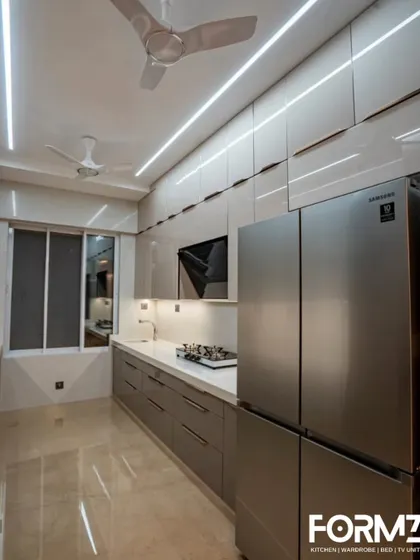 This parallel kitchen uses a neutral color palette with lacquered glass cabinets. The design integrates a large refrigerator and provides ample storage, making it ideal for families.