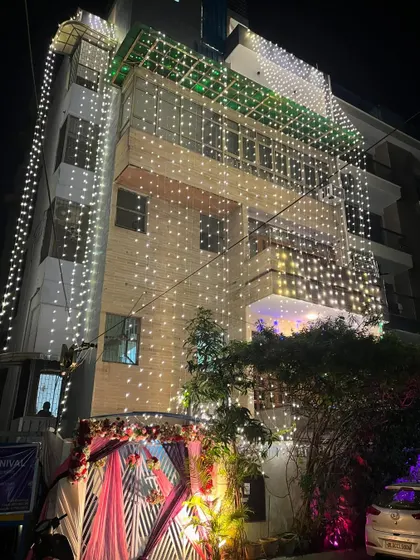 Another angle of the fully lit wedding house, showing the decorated gate and the fairy lights covering the entire building.