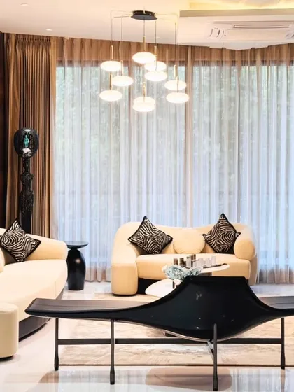 Natural light floods this living room, highlighting the clean lines of the furniture and the contrast between the dark wood paneling and the light-colored sofas.