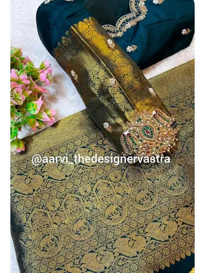A close up of the sleeve of the dark green blouse, featuring a traditional armlet or 'vanki' design embroidered directly onto the fabric.