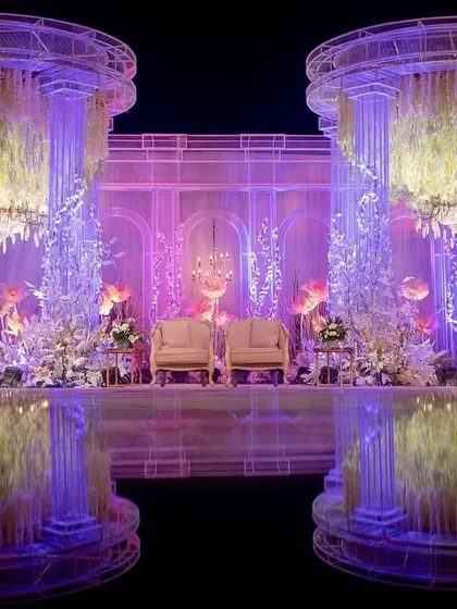 A closer look at the twin Romanesque pillars framing the stage. These structures were filled with cascading floral arrangements and illuminated from within, creating a soft, ethereal glow for this grand reception.