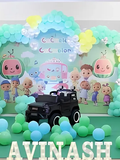 A close-up of the Cocomelon backdrop and balloon arch, highlighting the details of the characters and the pastel color scheme.