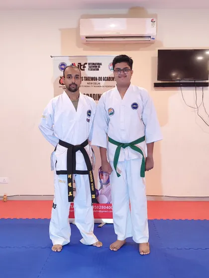 A teen student proudly wears his new green belt after passing his grading exam.