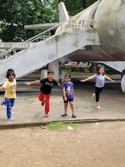 Kids practicing aeroplane pose in the park. This balancing pose builds strength and stability, and doing it outdoors makes it feel like we can really fly.