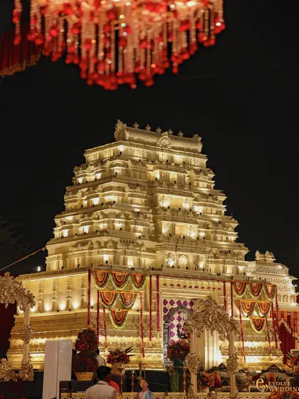 A low-angle shot emphasizing the towering height and intricate detail of the main temple structure. The lighting design carefully highlights each architectural layer, creating a sense of awe and reverence.