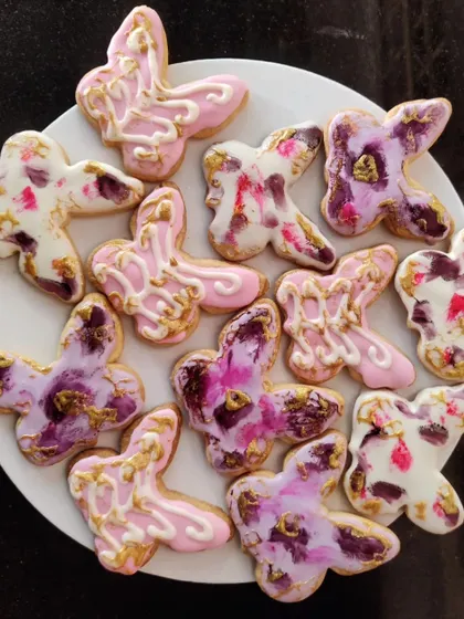 These beautiful butterfly-shaped cookies are decorated with a marbled icing effect and touches of gold leaf, making them an elegant treat for any occasion.
