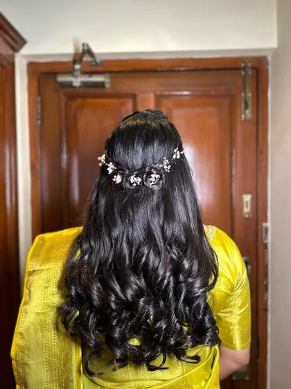 A close-up of the back, showing the intricate braid and the delicate pink floral hairpiece. This is a romantic choice for an engagement.