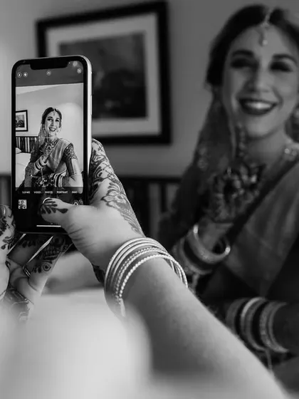 A behind-the-scenes candid. A bridesmaid takes a photo of the bride, who is smiling in the background. It's a modern, meta moment that I love to capture.