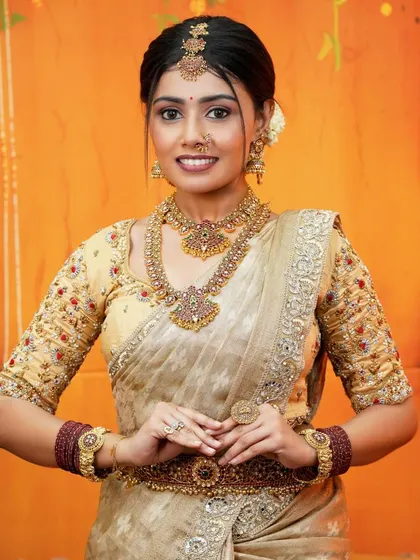 A full-length view of the cream and gold silk saree, showing its beautiful drape and the intricate detailing on the border. This is a perfect outfit for any traditional ceremony.