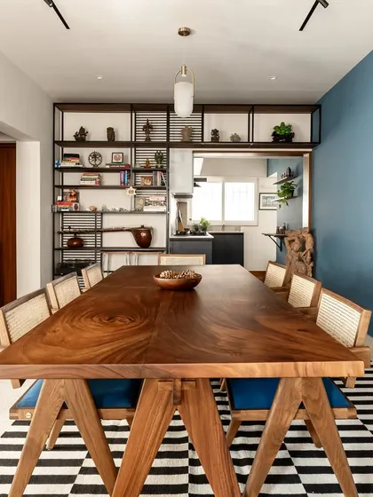 The dining room is the heart of the Keepsake home, featuring a large 8-seater table that encourages gathering. It is surrounded by open shelves displaying the client's artifacts, blending life, travel, and design into a single, cohesive narrative.
