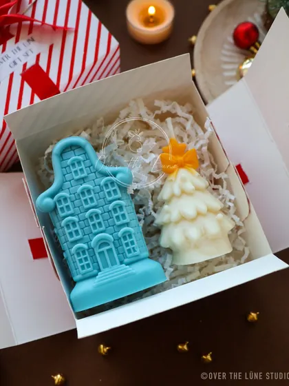 This whimsical Christmas gift set pairs a blue Amsterdam-style house candle with a cute, cartoonish Christmas tree candle.