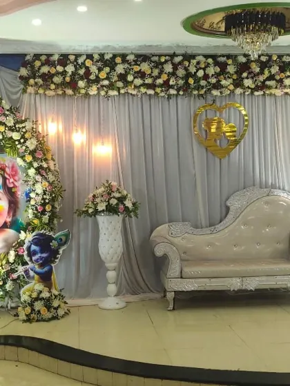 Celebrate your baby shower with a unique and joyful theme. This setup features a custom-printed circular backdrop of Yashoda and Krishna, framed with a delicate floral arrangement to bless the mother-to-be.