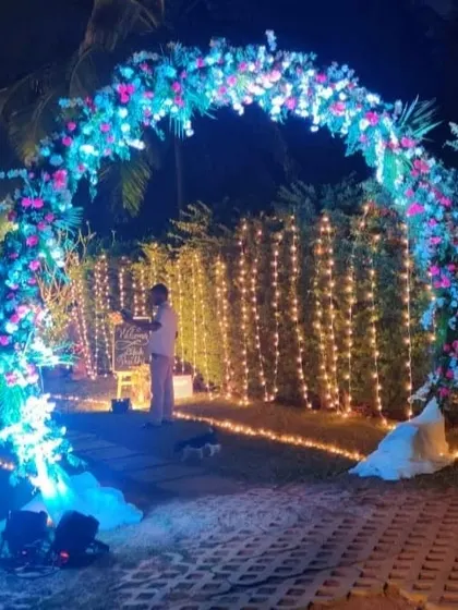 This illuminated floral arch creates a magical photo opportunity for an evening event. The combination of blue-toned lighting and fairy lights in the background produces a unique and memorable atmosphere.