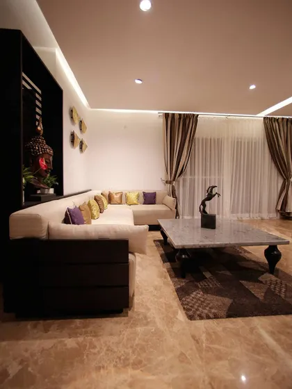 A living area where balance is achieved through subtle tones and distinct decor. The solid marble coffee table acts as an anchor, while a corner Buddha statue and carefully chosen cushions add layers of texture and tranquility.
