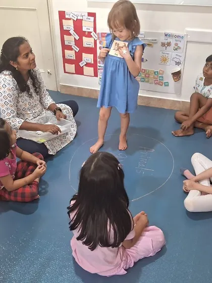 During circle time, we discuss the roles of different people in our community. Here, a child stands and shares her thoughts with the group, building public speaking confidence.