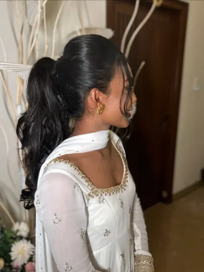 A high, bouncy ponytail with curls. This is a fun, youthful, and stylish look that's perfect for a sangeet or party.