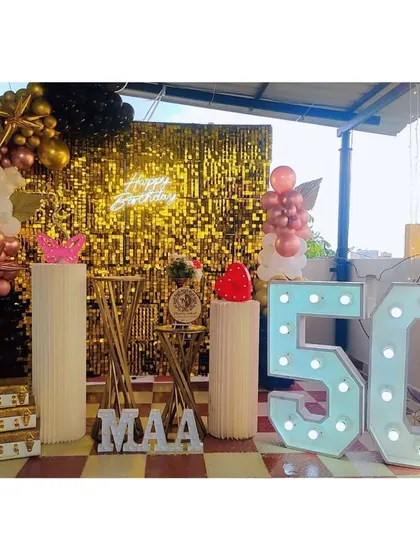 A grand 50th birthday celebration on a terrace. This setup features a brilliant gold sequin wall and large '50' marquee numbers, creating a festive and honorable tribute.