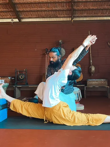 I assist a student in Hanumanasana (Monkey Pose or splits), using blocks for support. We teach how to approach advanced poses with intelligence and patience.