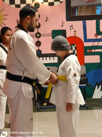 A student stands patiently as he is promoted to yellow belt. This moment signifies his readiness to learn new, more advanced techniques.