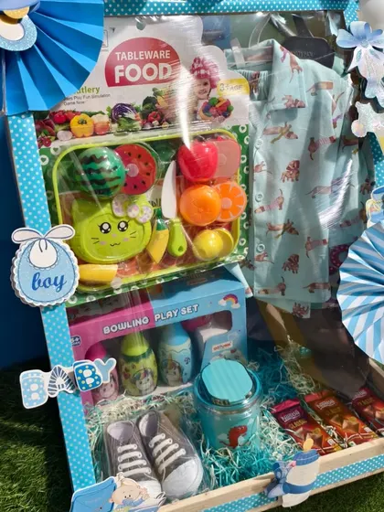 A close-up of the items in the first birthday hamper, including a fruit and vegetable cutting toy set.