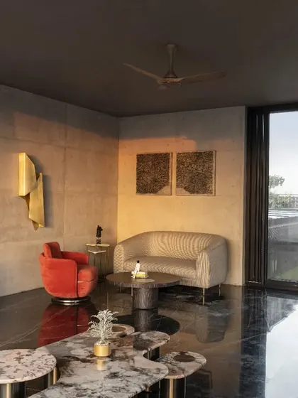 This terrace lounge at Swatantra Residence, with its exposed concrete and modern interiors, serves as a link between the indoors and the outdoor terrace, creating an ideal refuge for leisure and enjoyment.