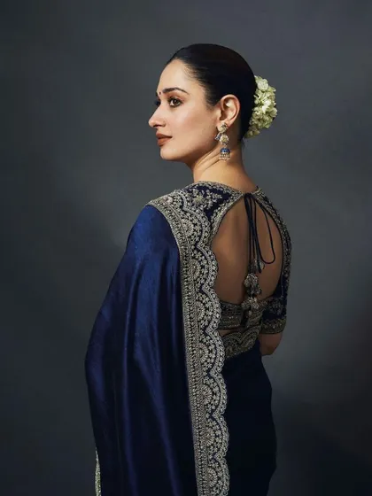 The back of this navy blue saree showcases the intricate embroidery on the blouse and the elegant tie-up detail. A timeless look for any formal occasion.