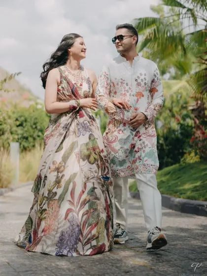 The couple, in matching printed outfits, takes a stroll through the venue's gardens. This showcases a relaxed, coordinated look perfect for a welcome event.
