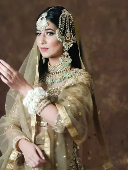 A model in a golden lehenga and mint-green jewellery, showcasing a soft and elegant look.