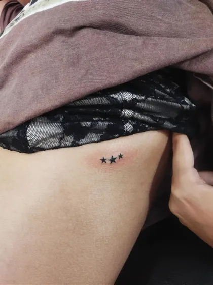 Three tiny stars on the ribcage. This is a classic minimalist design that can represent guidance, family, or personal milestones.