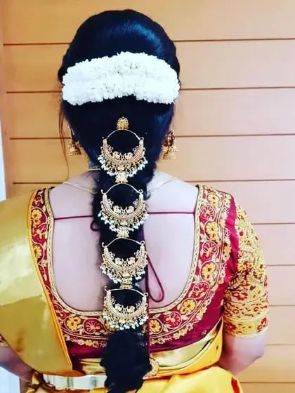 A traditional braid adorned with multiple large, crescent-shaped gold hairpieces (chandrakor) for a regal look.