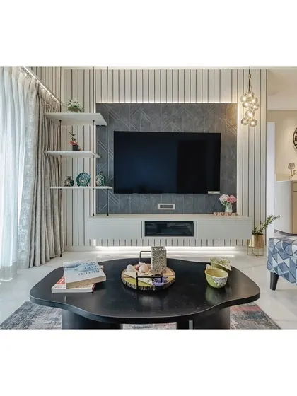 This living room features a custom-designed TV unit with a textured charcoal panel and vertical fluting on the wall. The combination of different materials and patterns adds depth and a sophisticated, tactile quality to the space.