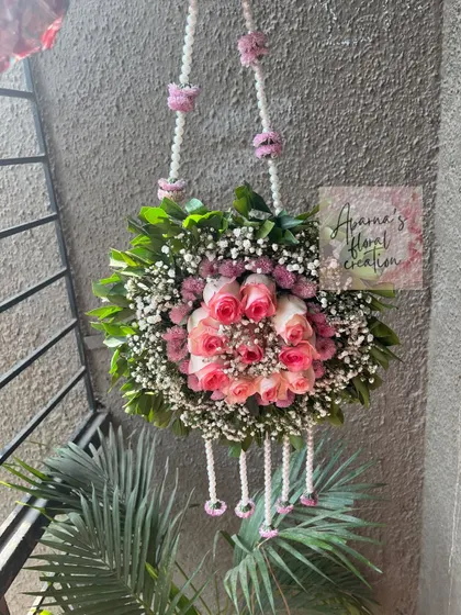 A hanging floral purse, or 'potli', made with a ball of pink roses and baby's breath. This is a beautiful accessory for the mom-to-be.