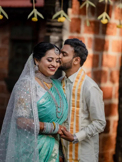 A sweet and tender moment between the couple. The groom's kiss on the bride's cheek captures the affection and romance of their wedding day.