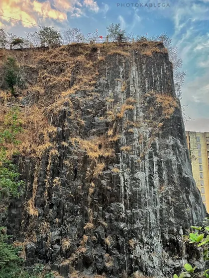 The sheer black rock face of the Gilbert Hill monolith, a unique geological formation in Mumbai.