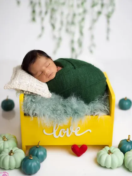 A different take on the same setup, with the baby swaddled in a green wrap. This shows the versatility of a single set of props to create multiple beautiful shots.