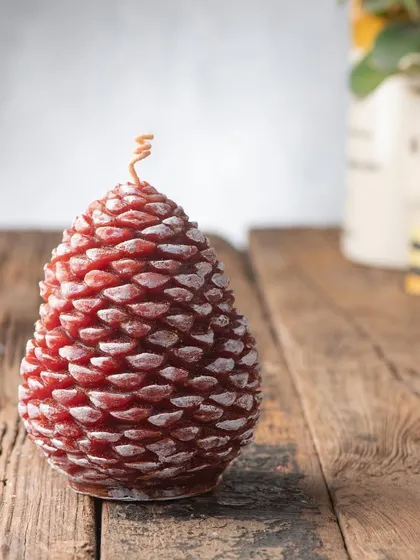 This large, red pinecone candle has a touch of white frost, making it look like it was just brought in from a snowy forest.