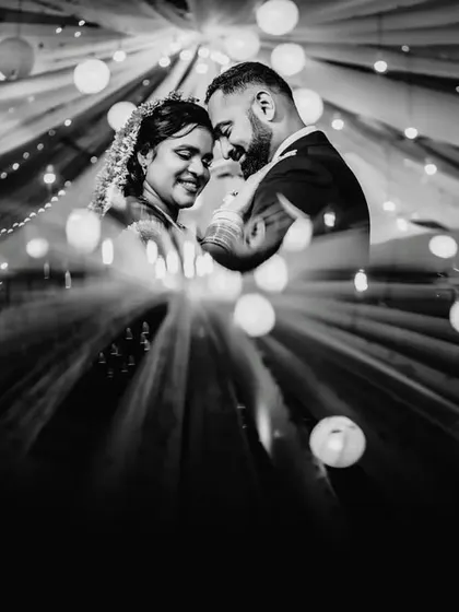 A creative black and white portrait using a prism or reflection to create a starburst effect with the lights. This is a unique and artistic couple shot.