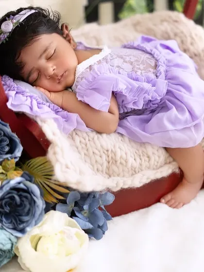 An angled shot of the newborn girl in her floral basket, highlighting the soft textures and colors of the setup.