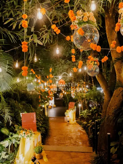 As night falls, the Haldi venue is transformed with strings of Edison bulbs and disco balls mixed with marigold garlands.