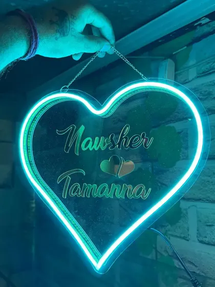 A heart-shaped neon sign, personalized with a couple's names. This makes a stunning piece of wall art for a bedroom.